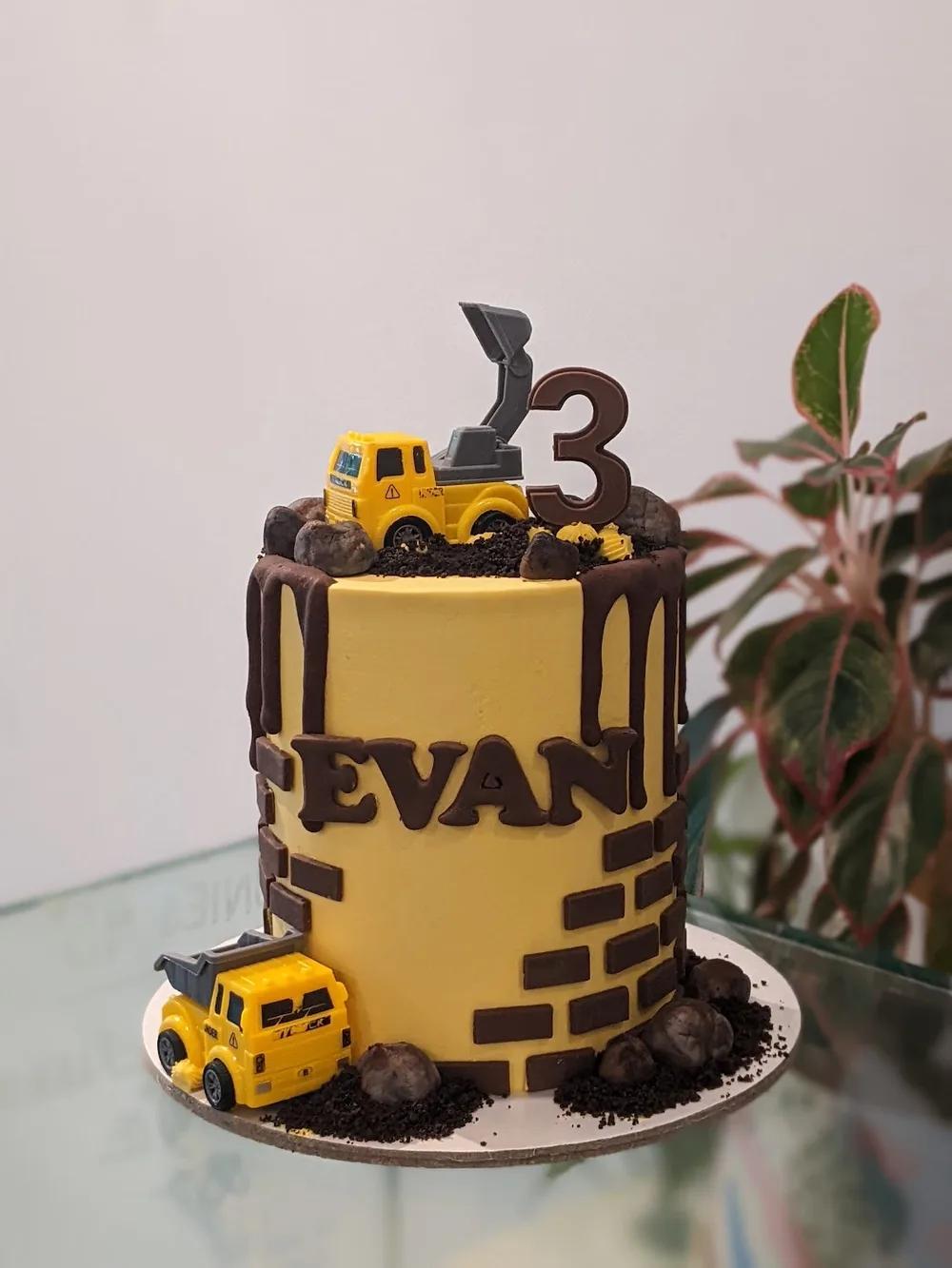 yellow construction cake with a chocolate drip, brick wall detail and toy diggers