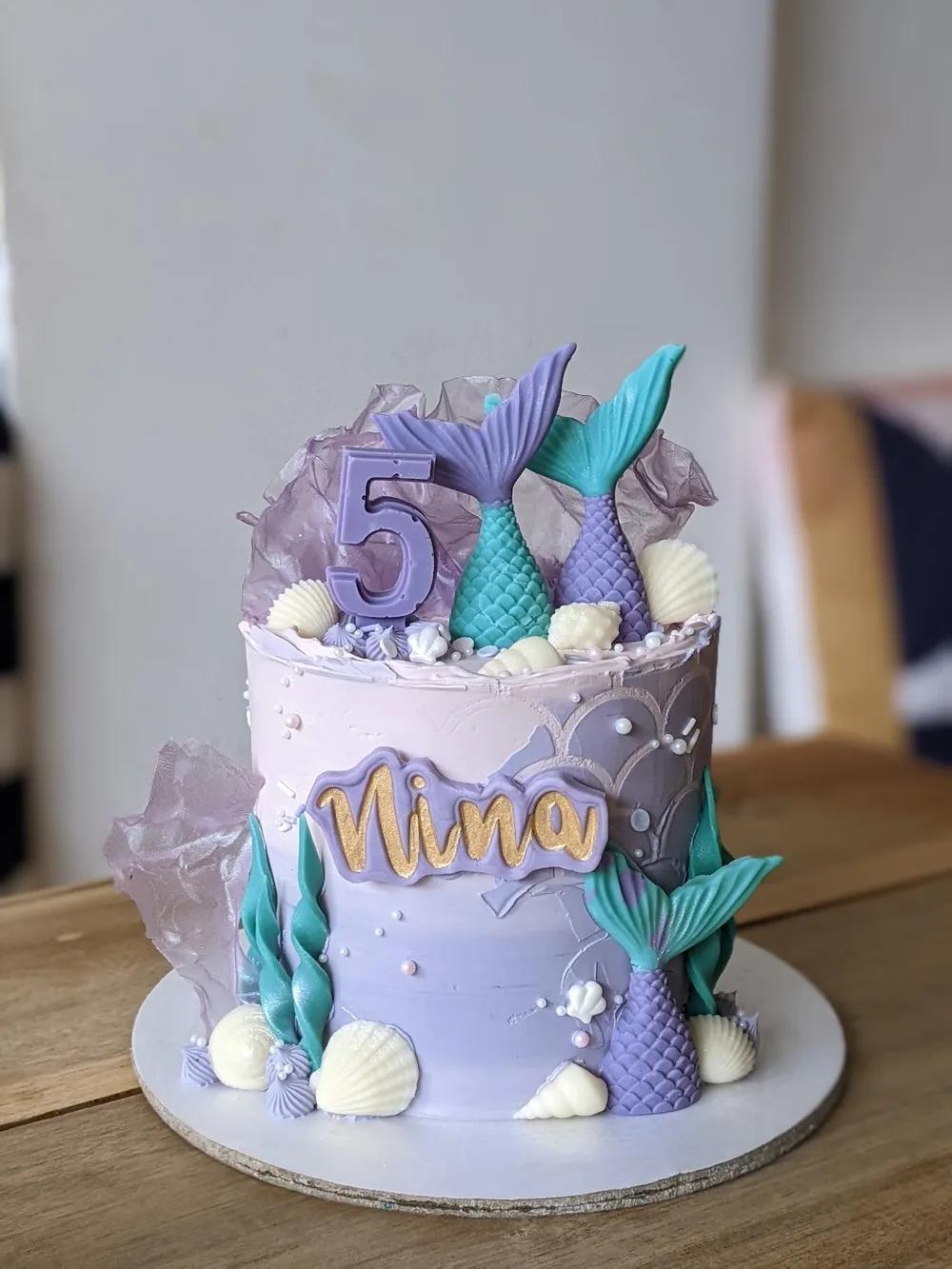 lilac mermaid cake with teal chocolate tails, shells and sugar crystals