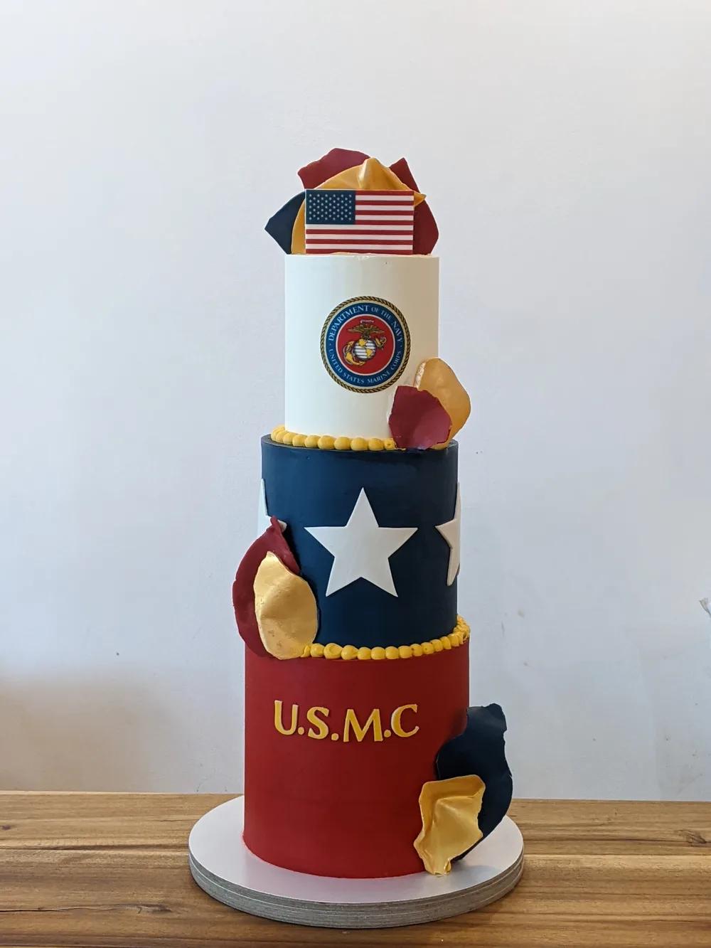 three-tier red, navy and white cake with a star, gold-edged chocolate shards and an edible emblem