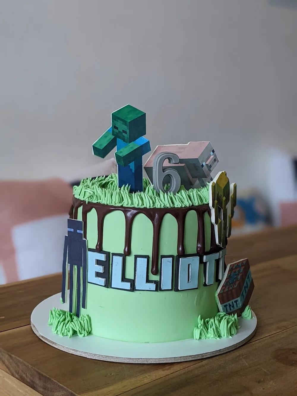 green minecraft cake with a chocolate drip, piped grass and character toppers