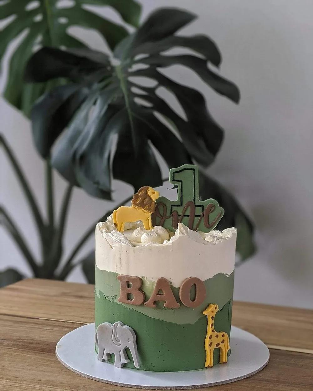 green safari first-birthday cake with lion, giraffe and elephant cookies
