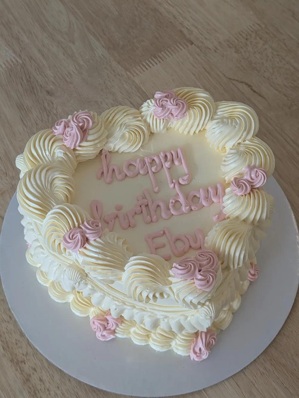 heart-shaped vintage cake with cream shell piping, pink rosettes and a piped birthday message